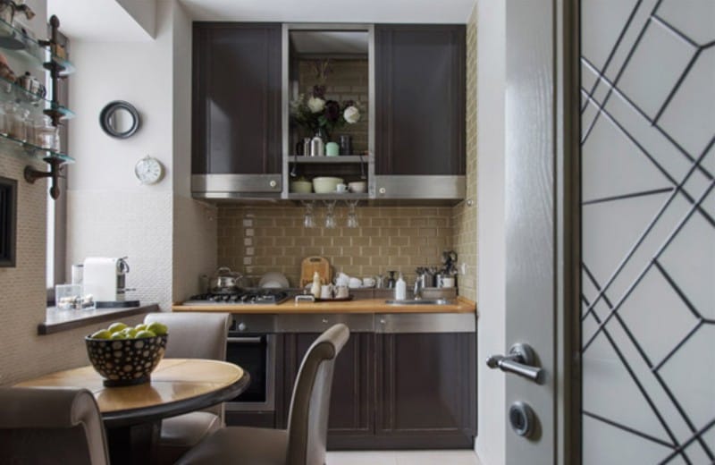 A small clock in the interior of a small kitchen