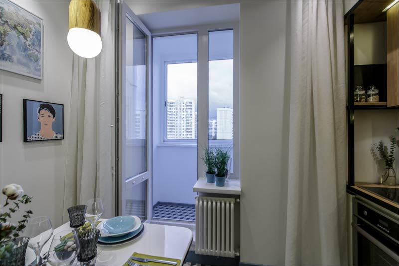 Interior of modern kitchen with balcony and white curtains